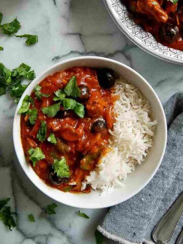 pastele stew in serving bowl, with rice to the side and 1 serving dished out on countertop.