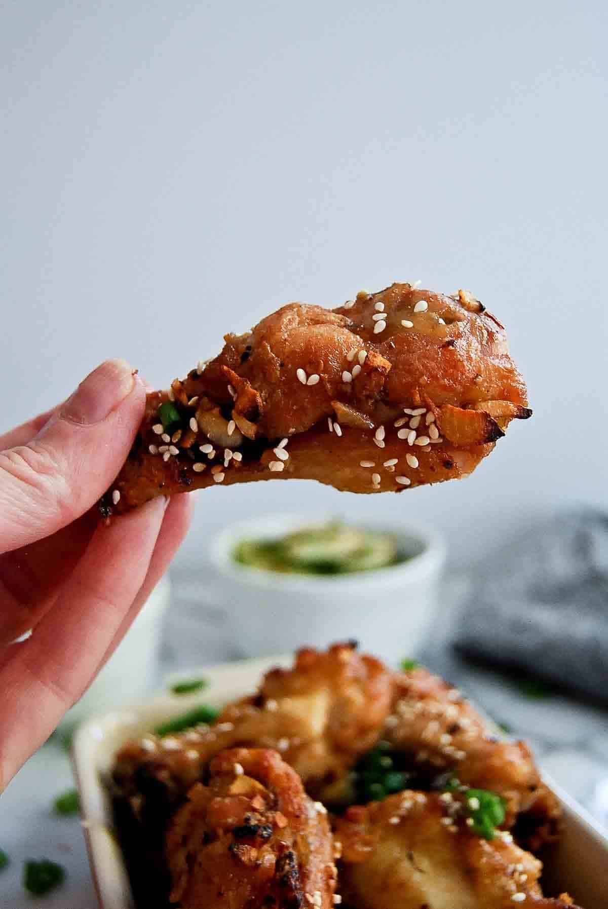 hand holding a soy garlic chicken drumette.