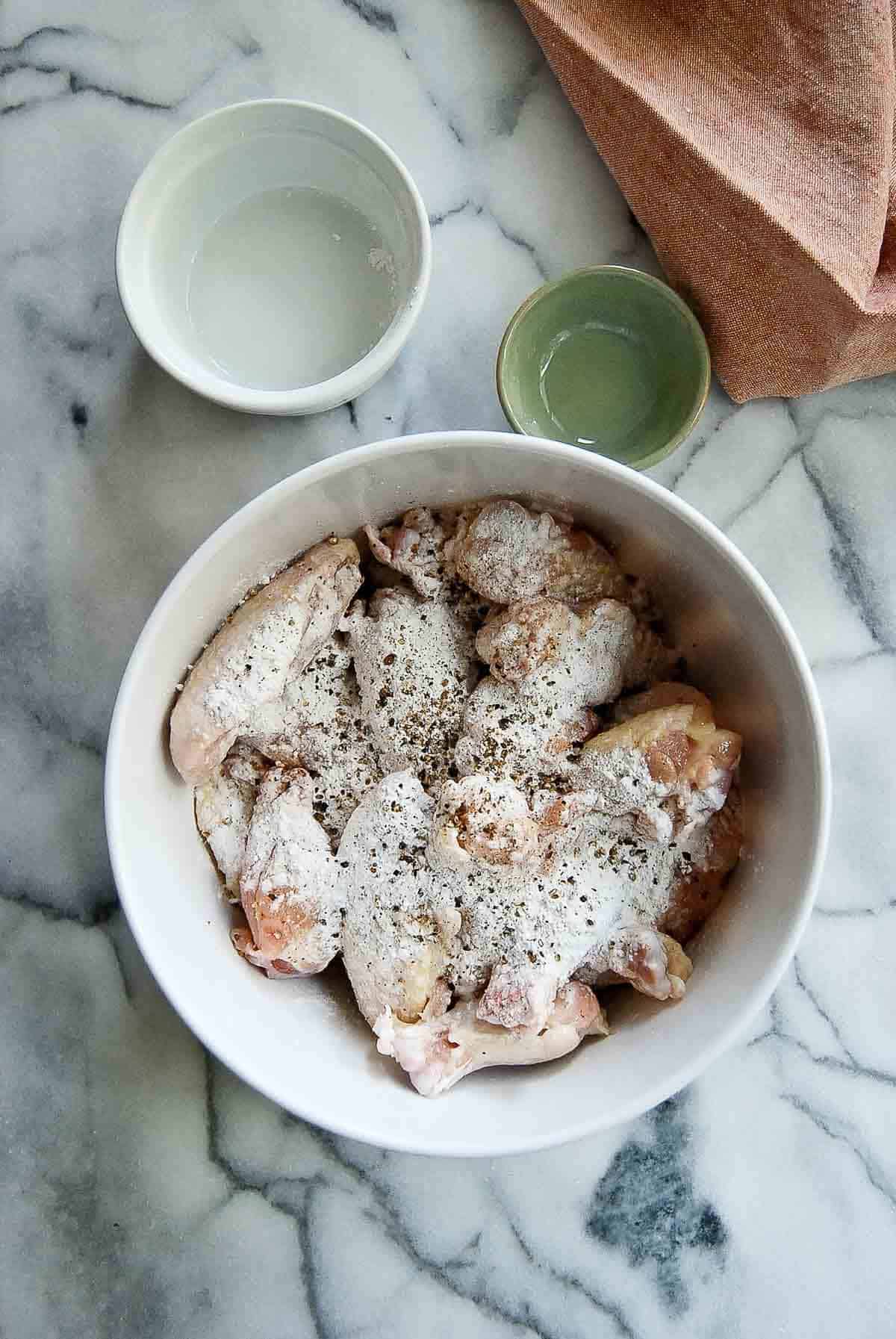 chicken wings tossed with baking powder in a bowl.