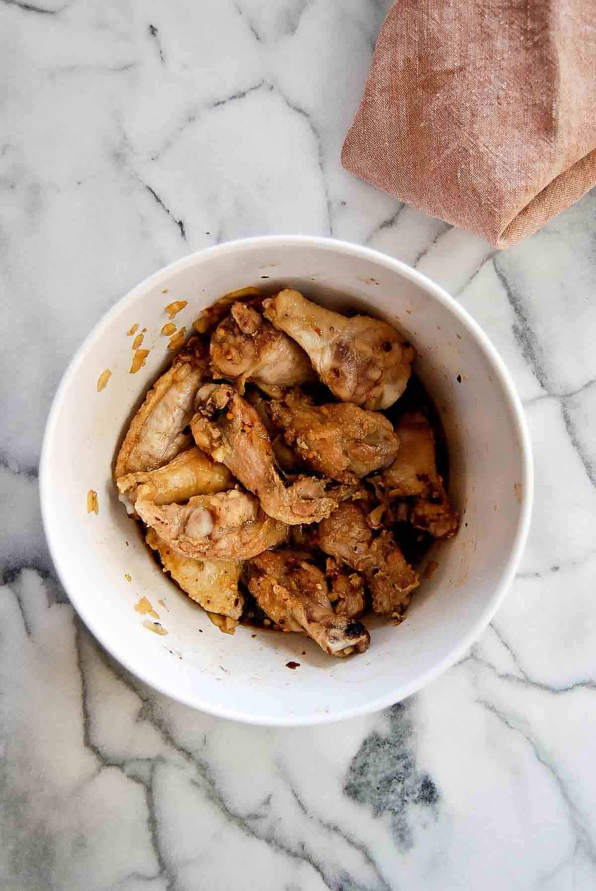 baked wings tossed with soy garlic sauce in bowl.