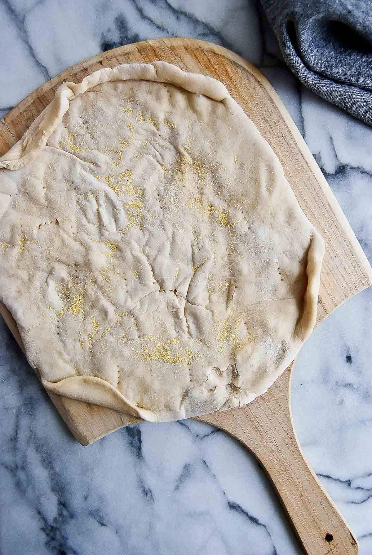 pre baked pizza dough on pizza peel.