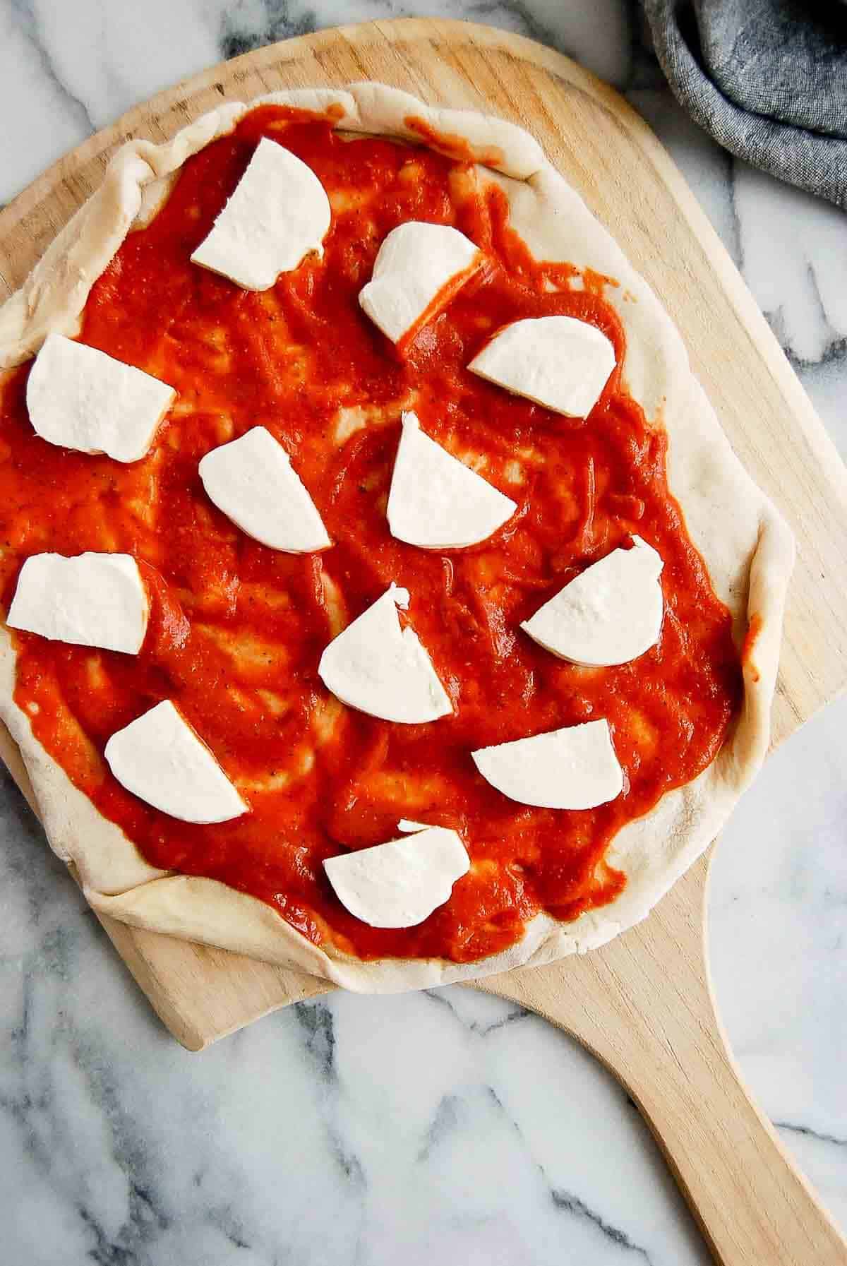 pizza dough with marinara sauce and fresh mozzarella on the top.