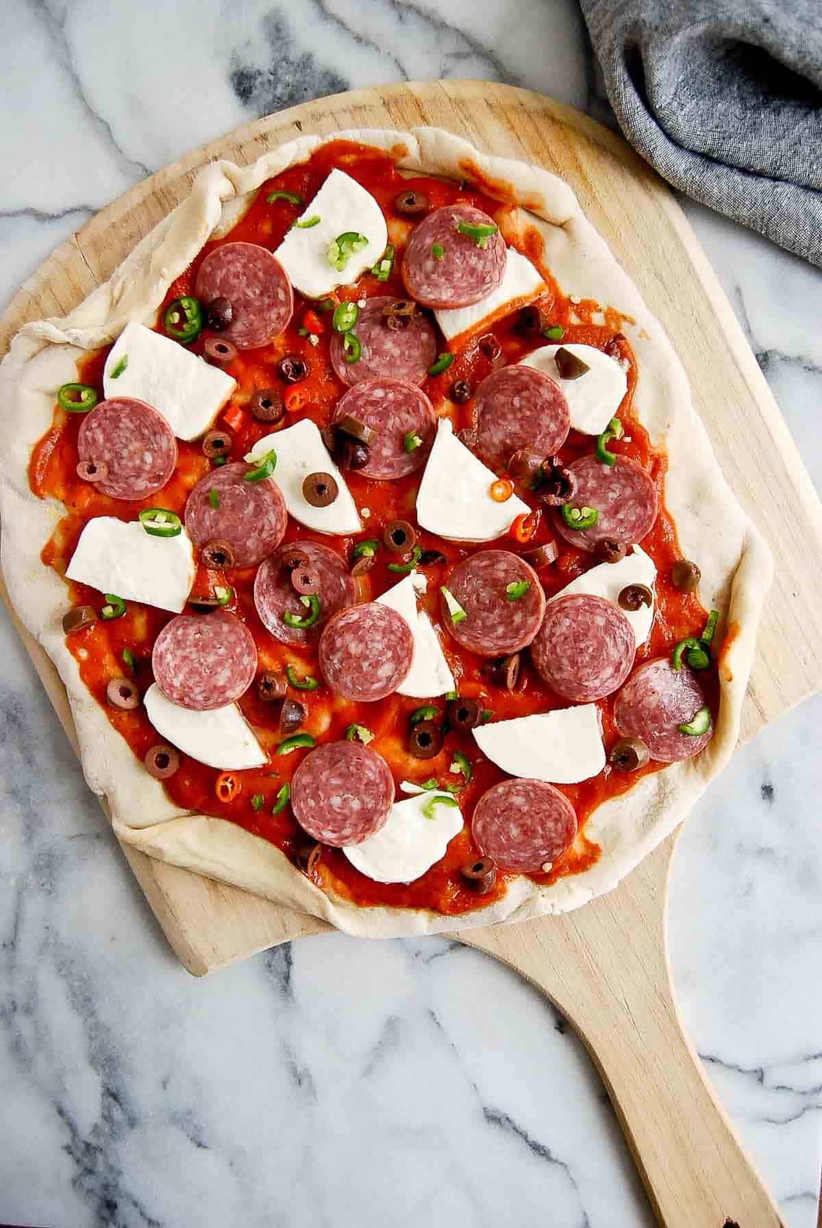 pizza diavola, pre-baked, with tomato sauce, mozzarella, hot salami, spicy peppers, and kalamata olives.