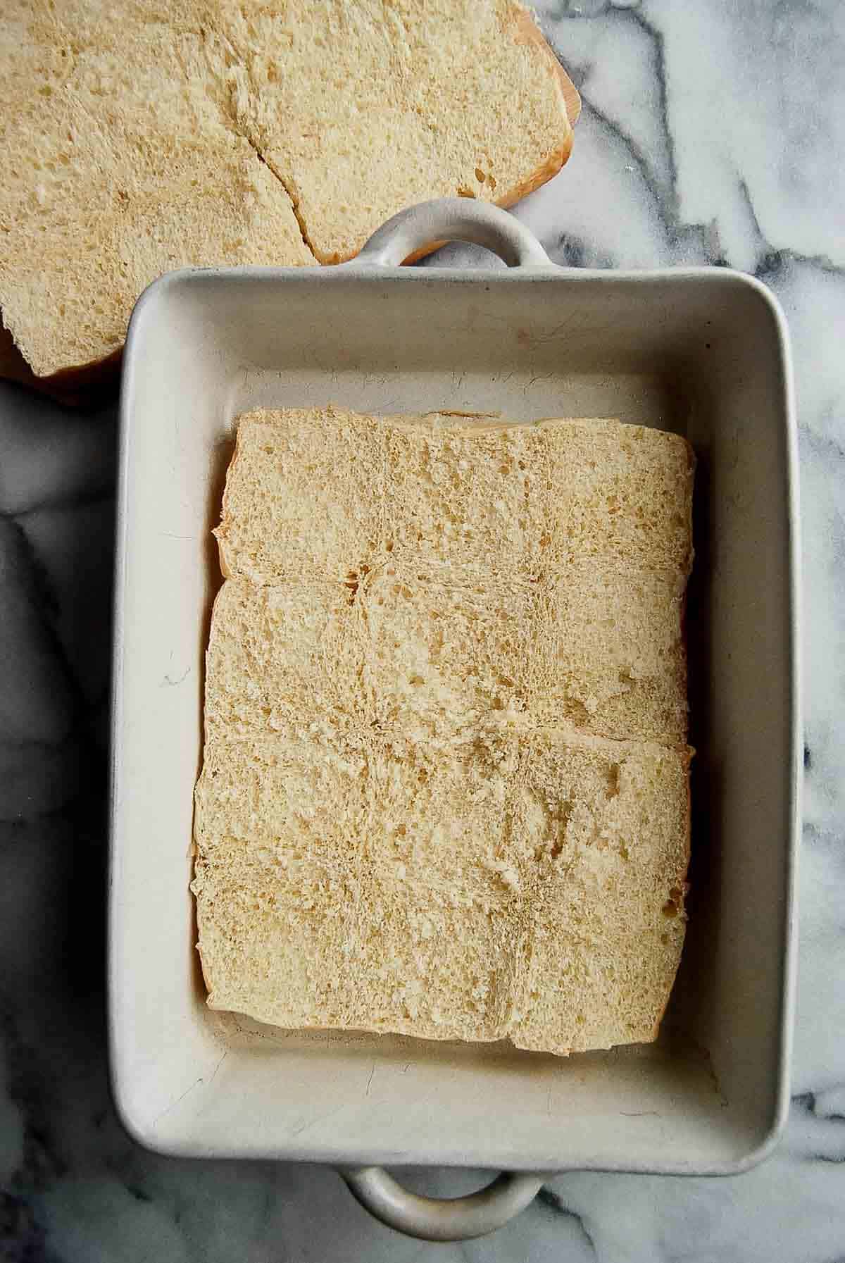 bottom slab of kings hawaiian rolls in prepared baking dish.