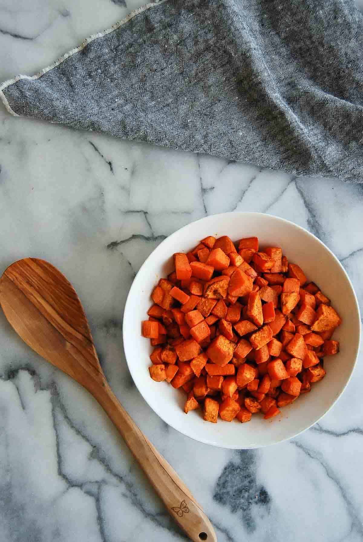 air fryer sweet potato cubes in bowl on countertop.