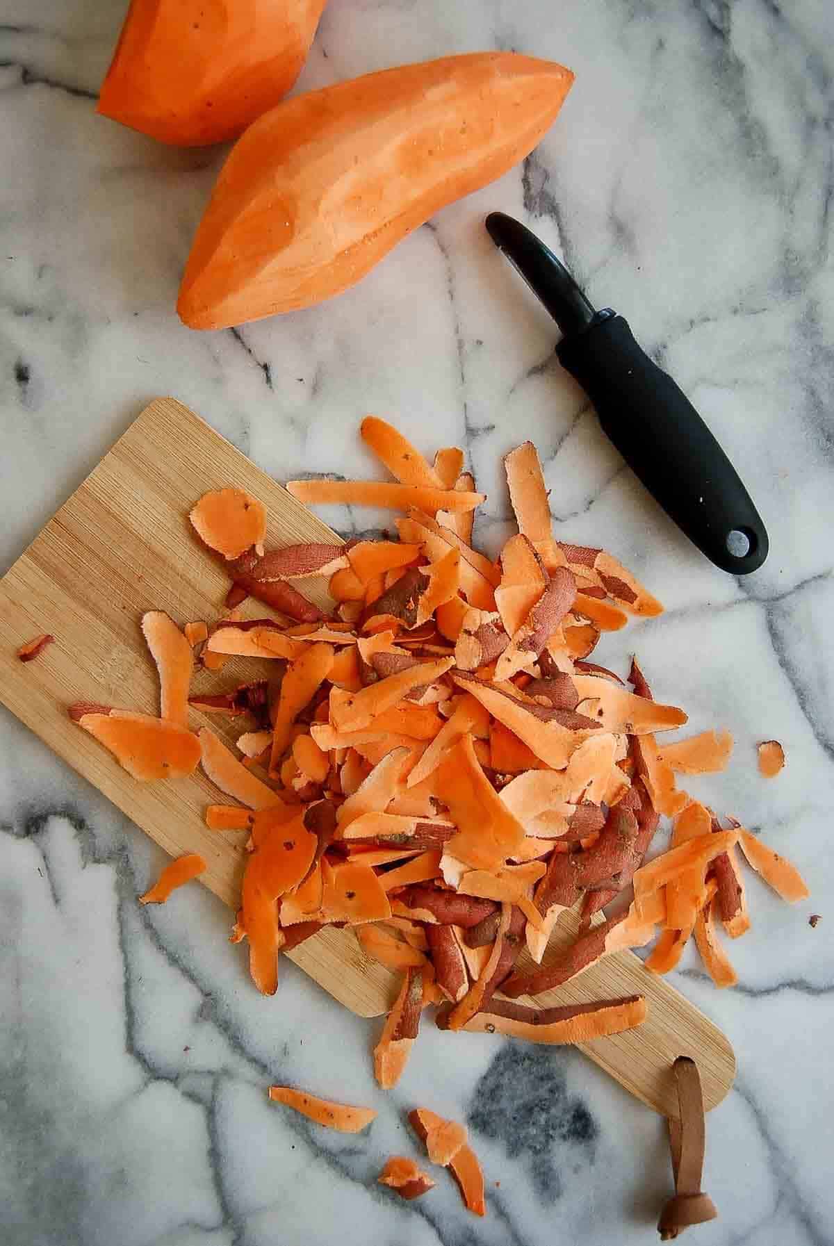 peeled sweet potatoes on countertop with shavings.