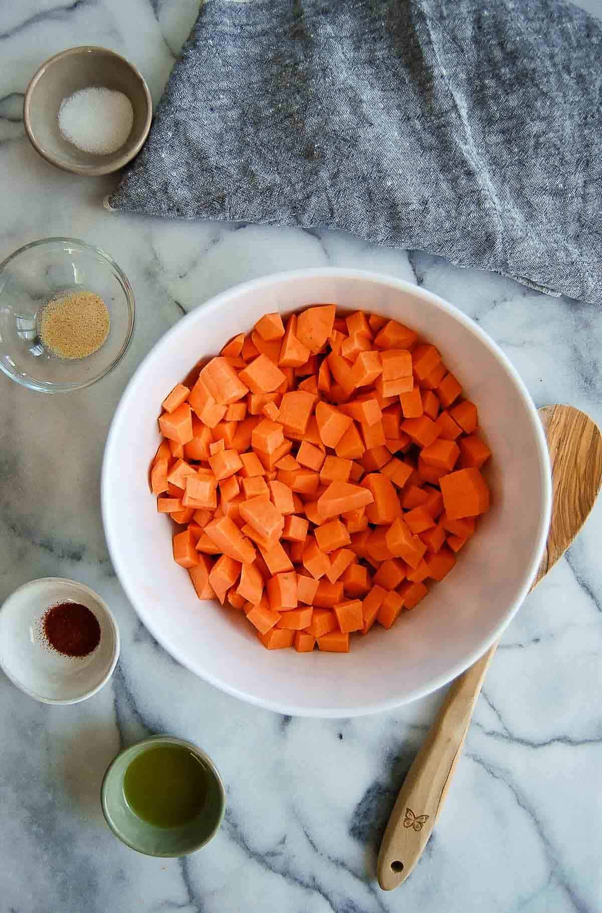 sweet potato cubes in bowl with seasoning to the side.