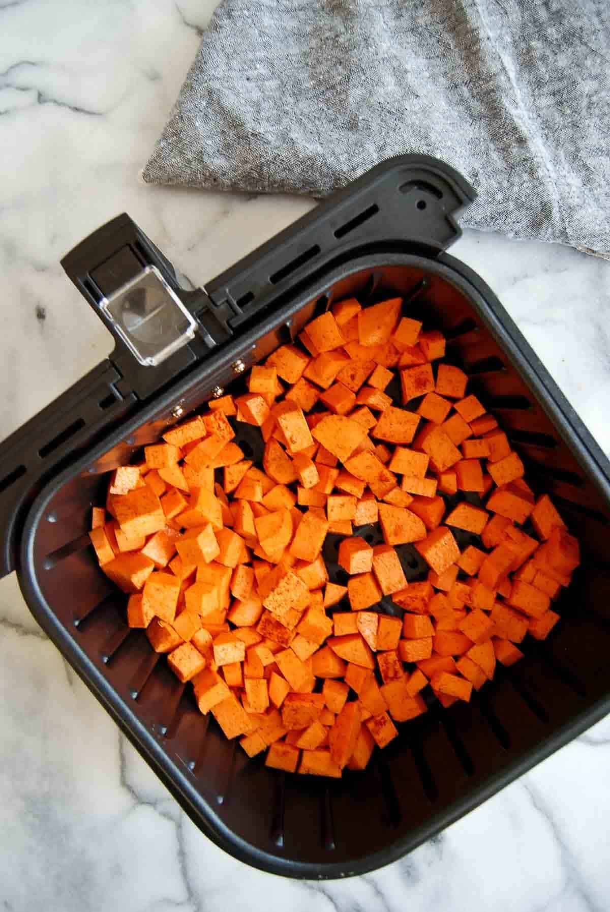 savory sweet potato cubes in air fryer basket.