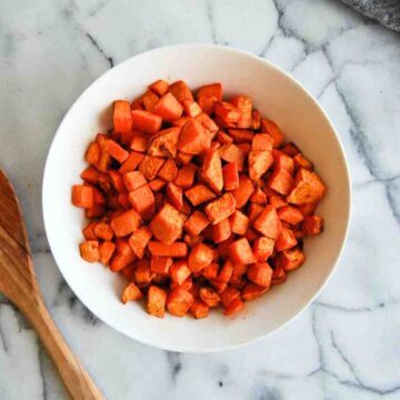 air fryer sweet potato cubes in bowl on countertop.