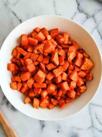 air fryer sweet potato cubes in bowl on countertop.