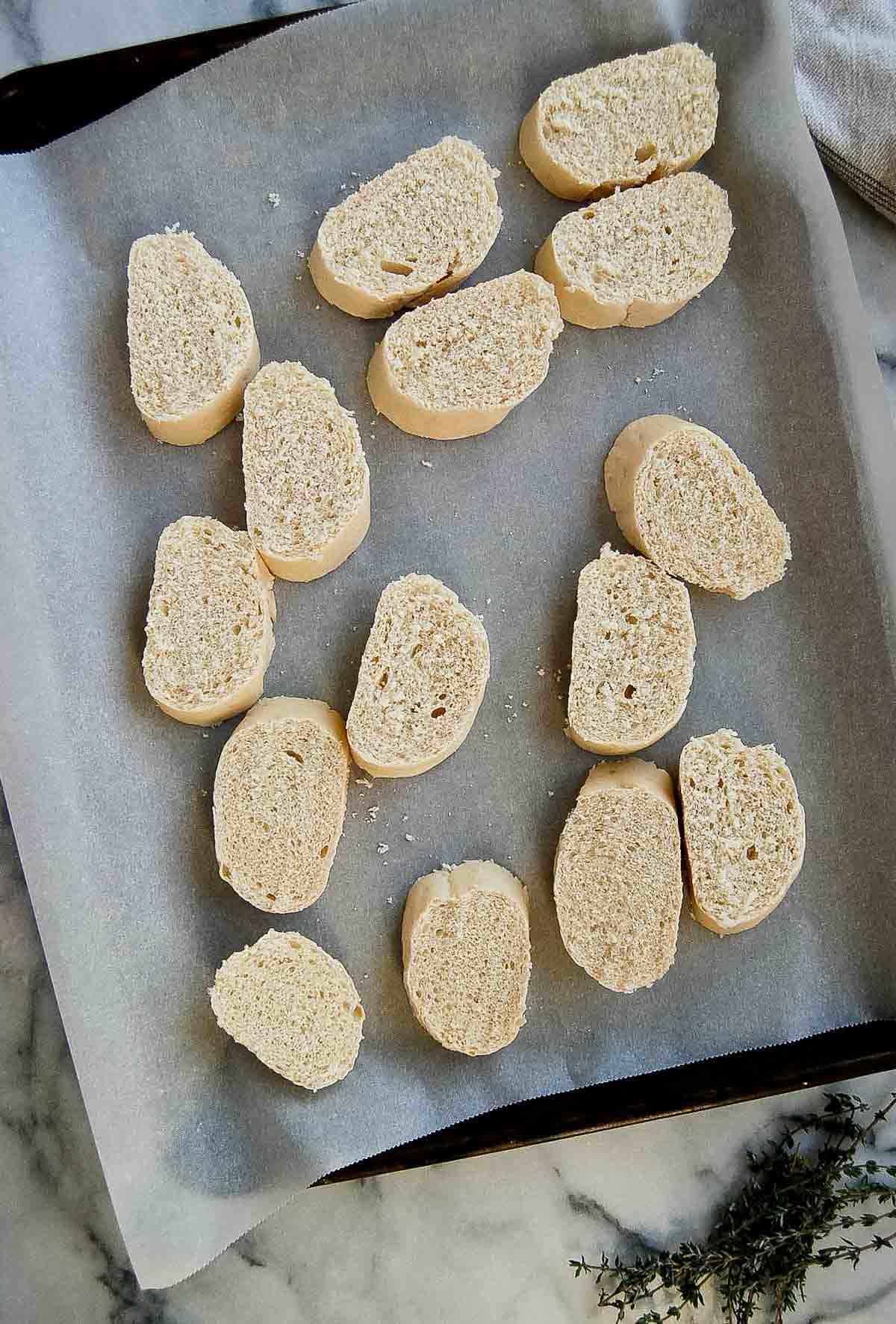 sliced baguette pieces on sheet pan.
