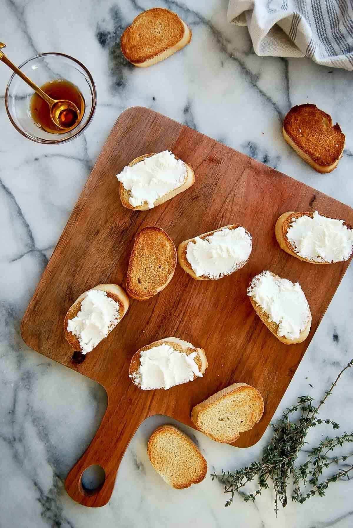 baguette slices with goat cheese spread and honey and thyme on the side.