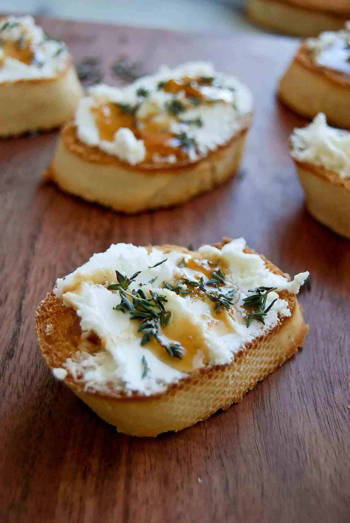 side view of goat cheese crostini with thyme and honey.