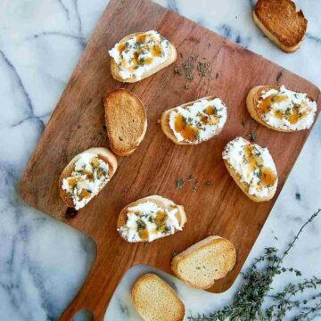 goat cheese crostini with thyme and honey on cutting board.