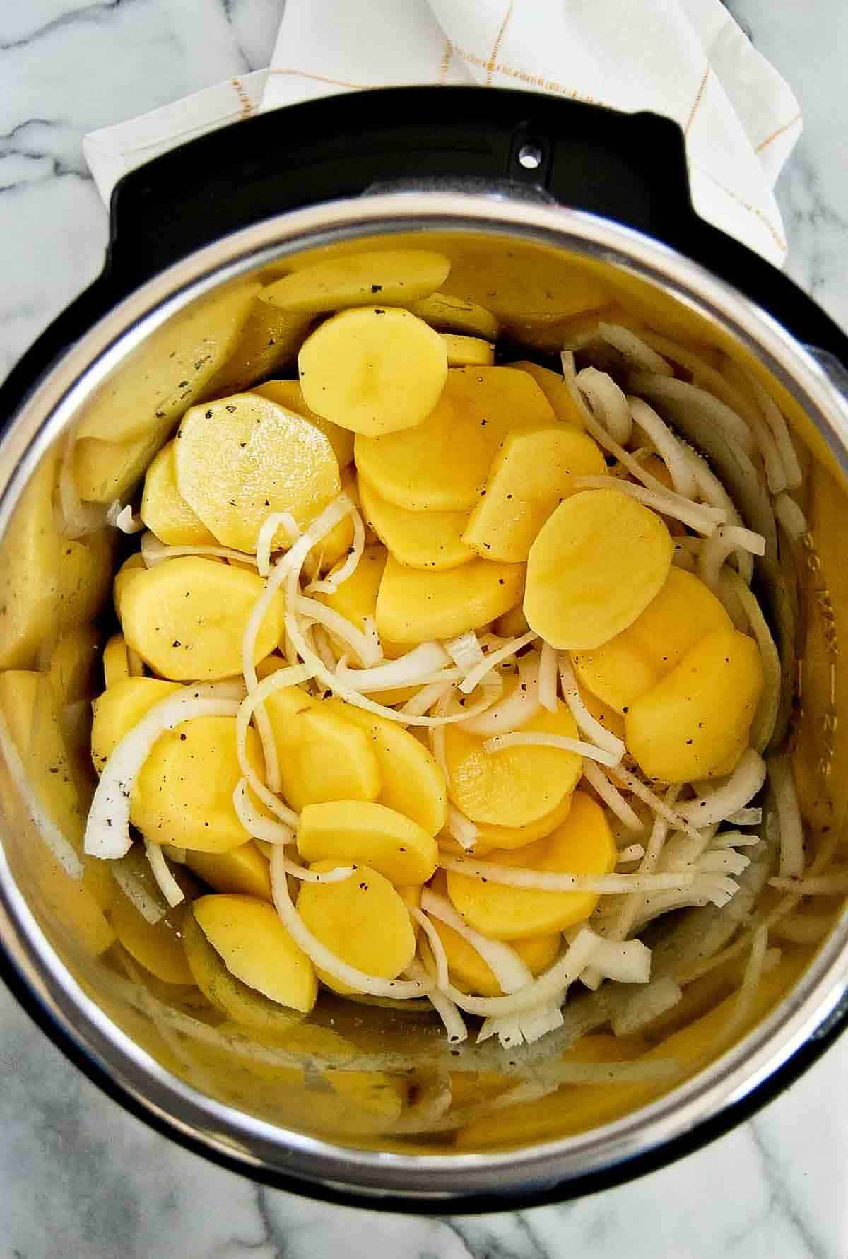 peeled and sliced potatoes and onions in instant pot.