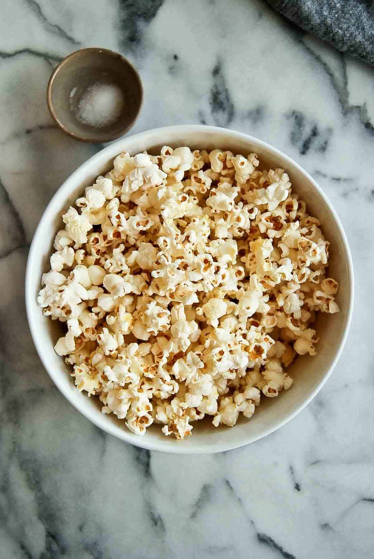 buttered popcorn with small bowl of salt next to it.