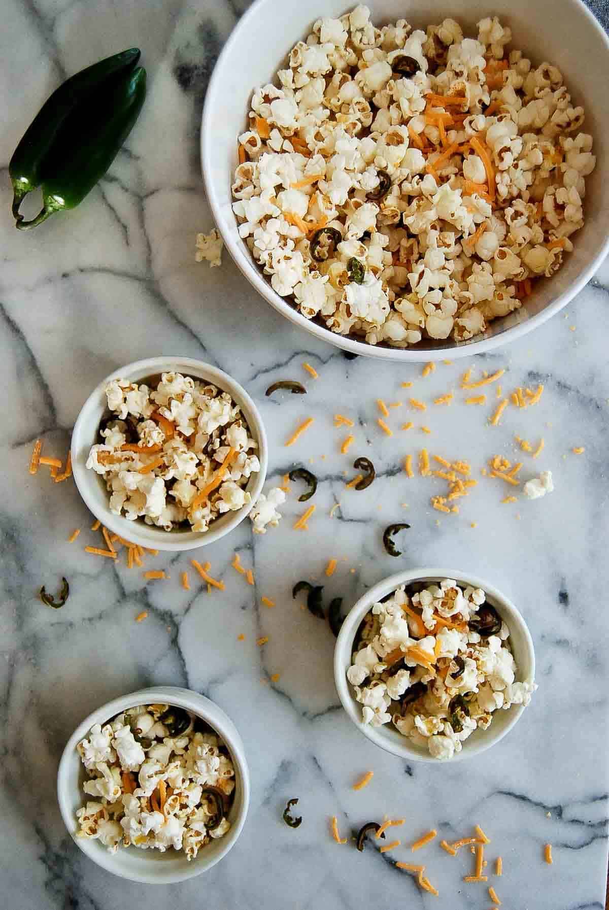 Bowl of jalapeno cheddar popcorn with three smaller servings next to it.