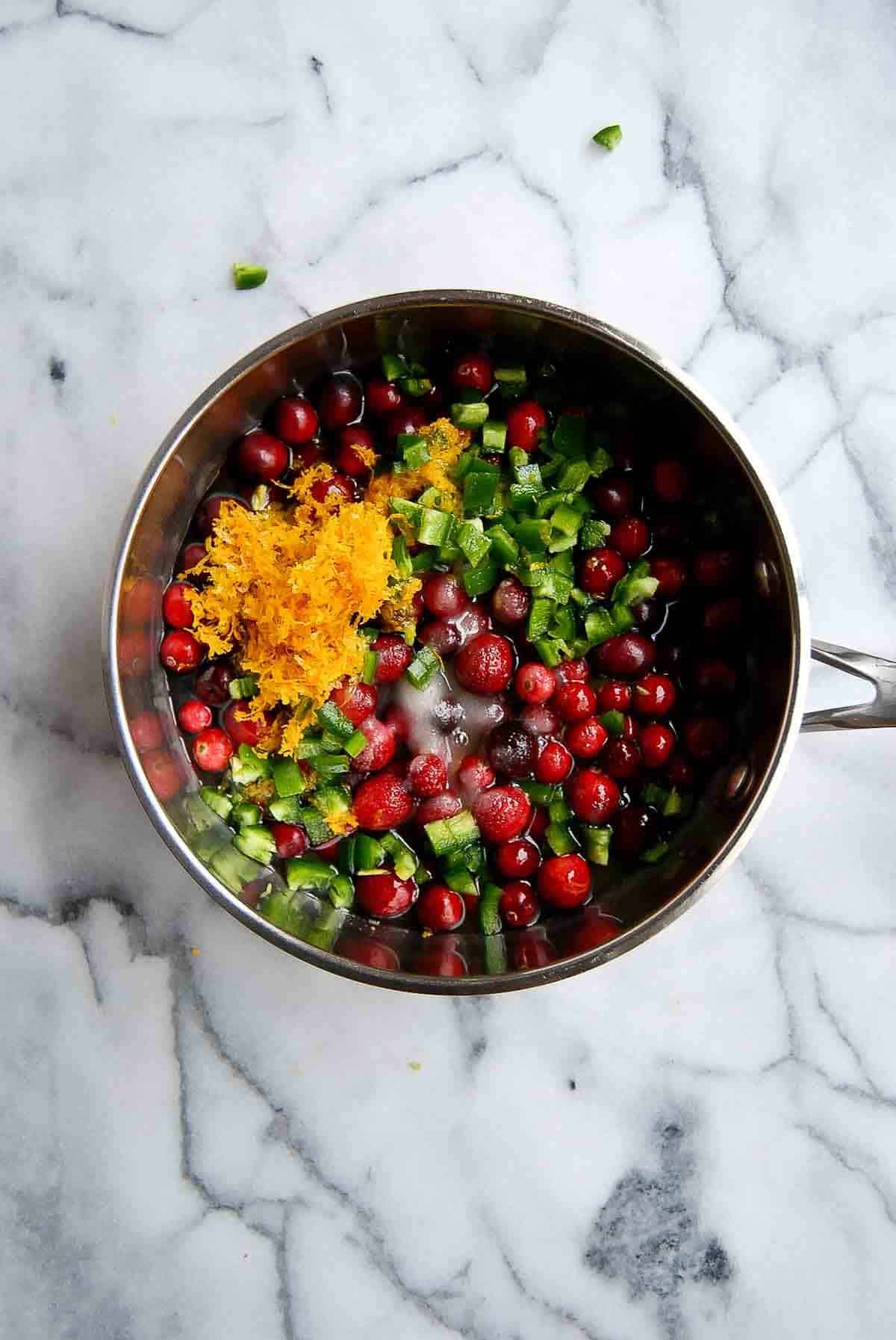 whole cranberries in saucepan with sugar, water, orange juice, orange zest and jalapeno peppers.