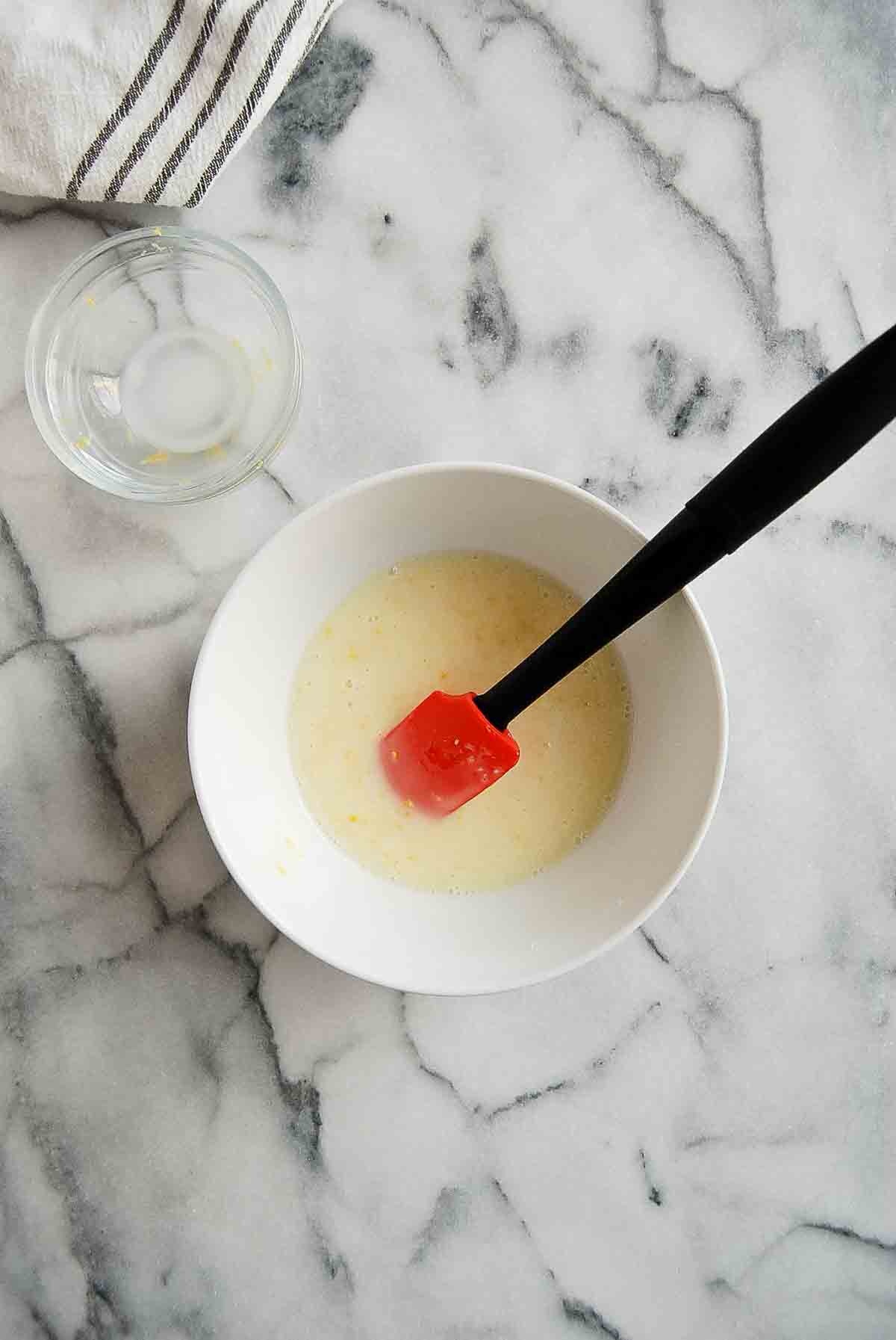 mixed lemon glaze icing in bowl with rubber spatula.