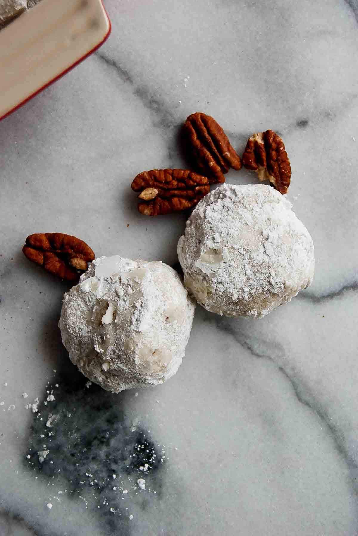 2 snowball cookies on countertop.