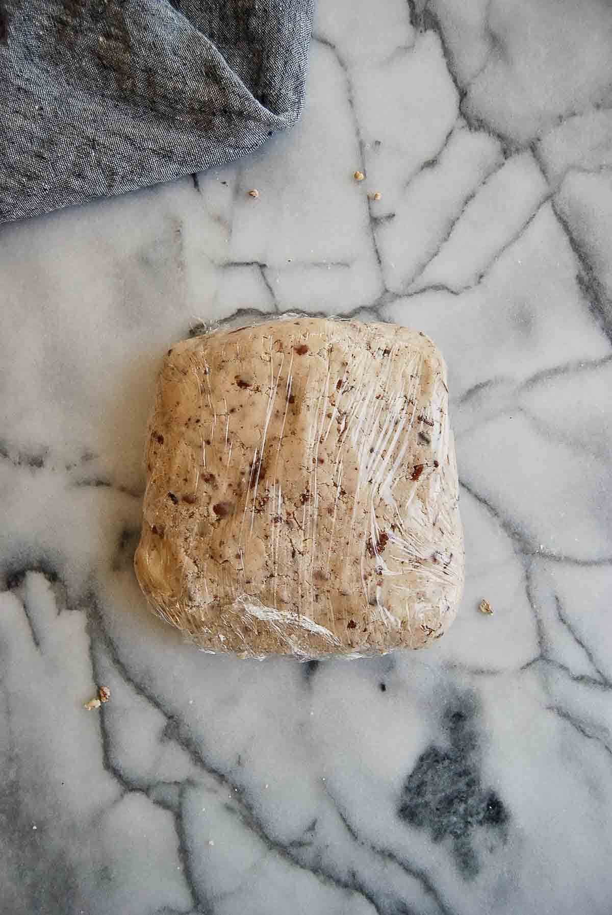 dough for mexican cookies (snowballs) wrapped in plastic on countertop.