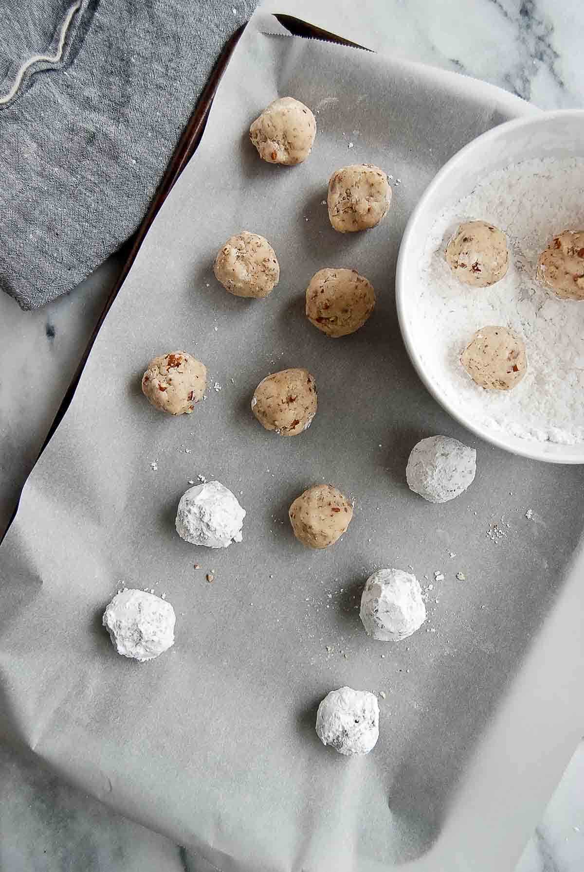 mexican cookie dough balls rolled in powdered sugar on cookie sheet.