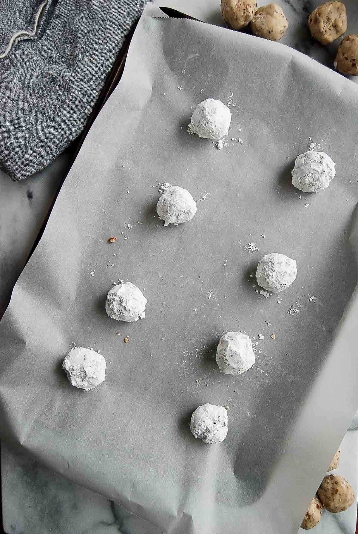 mexican cookie dough balls rolled in powdered sugar on cookie sheet.