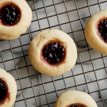 closeup of raspberry thumbprint cookie on cooling rack.