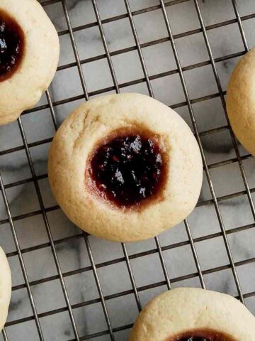 closeup of raspberry thumbprint cookie on cooling rack.