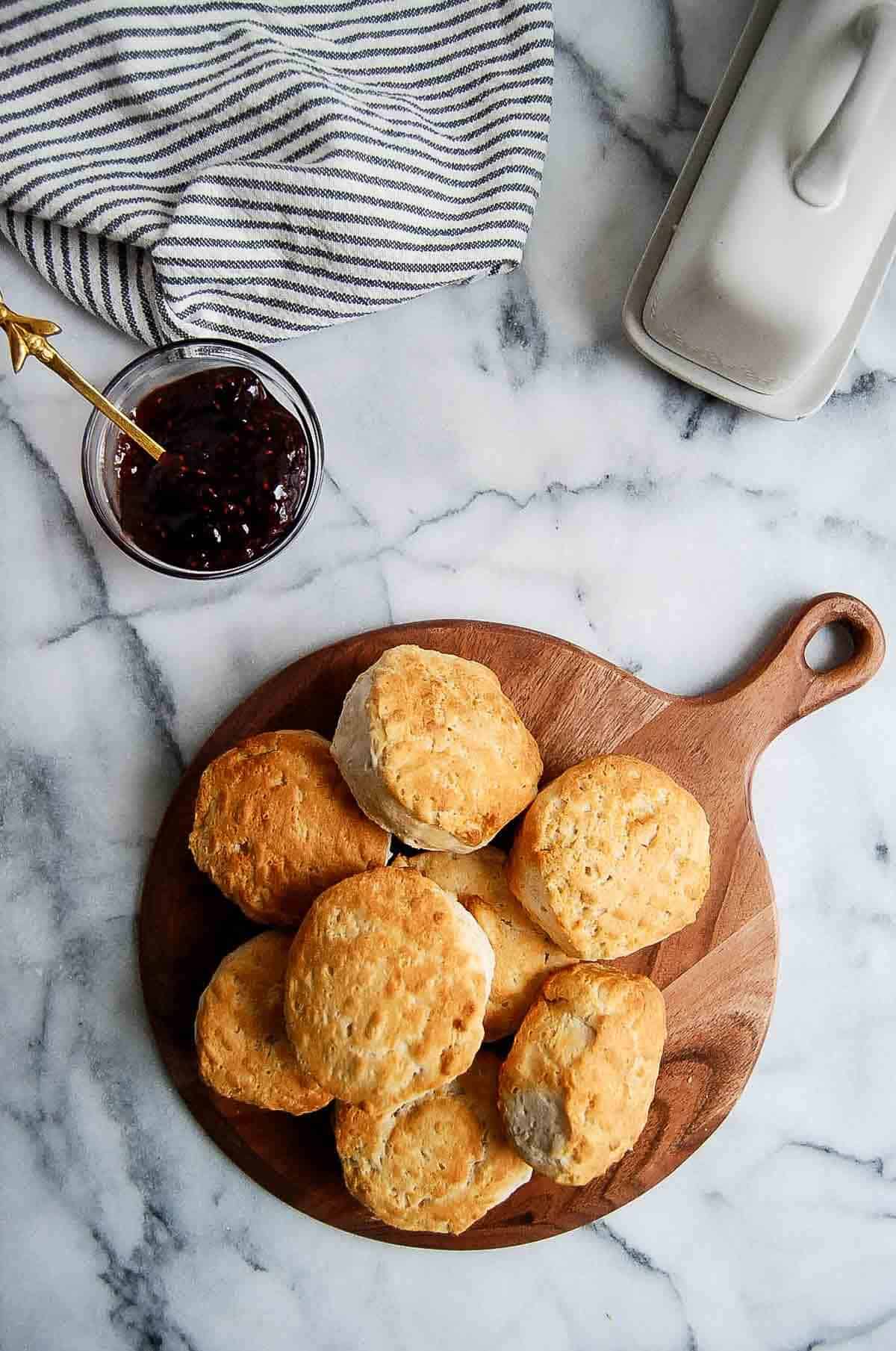 stack of air fried biscuits on cutting board with jelly bowl to the side.