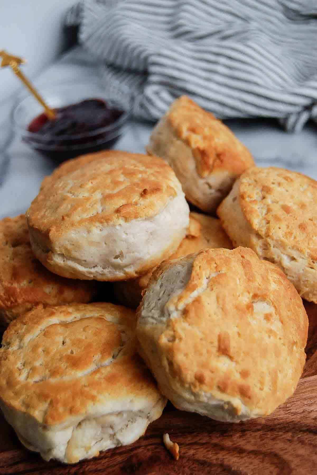 side view of air fryer biscuits stacked on cutting board with bowl of jelly in background.