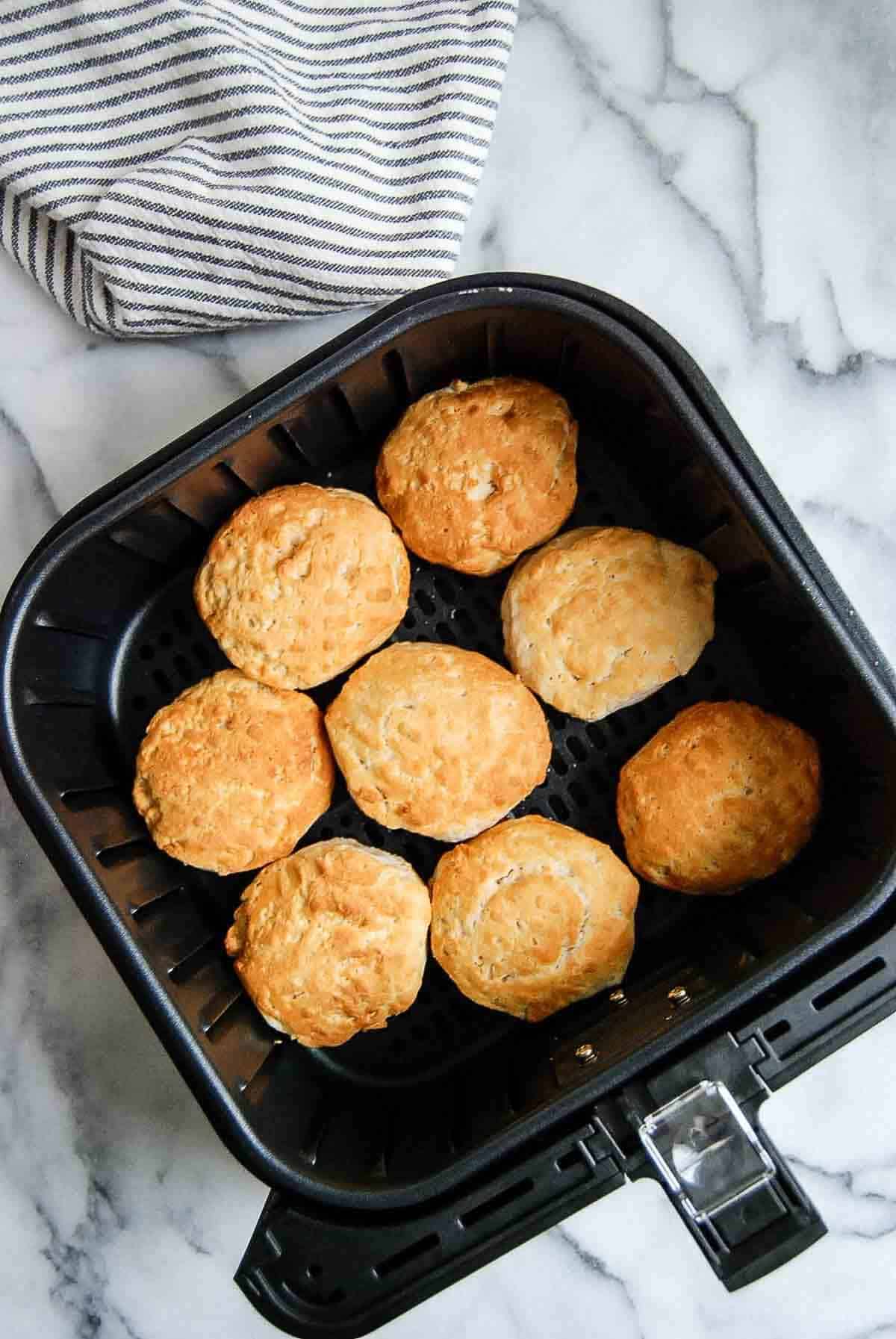 air fryer basket with baked biscuits inside.