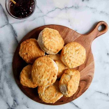 stack of air fryer biscuits on cutting board with bowl of jelly on the side.