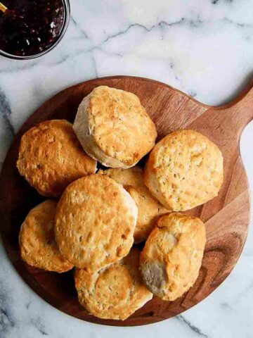 stack of air fryer biscuits on cutting board with bowl of jelly on the side.