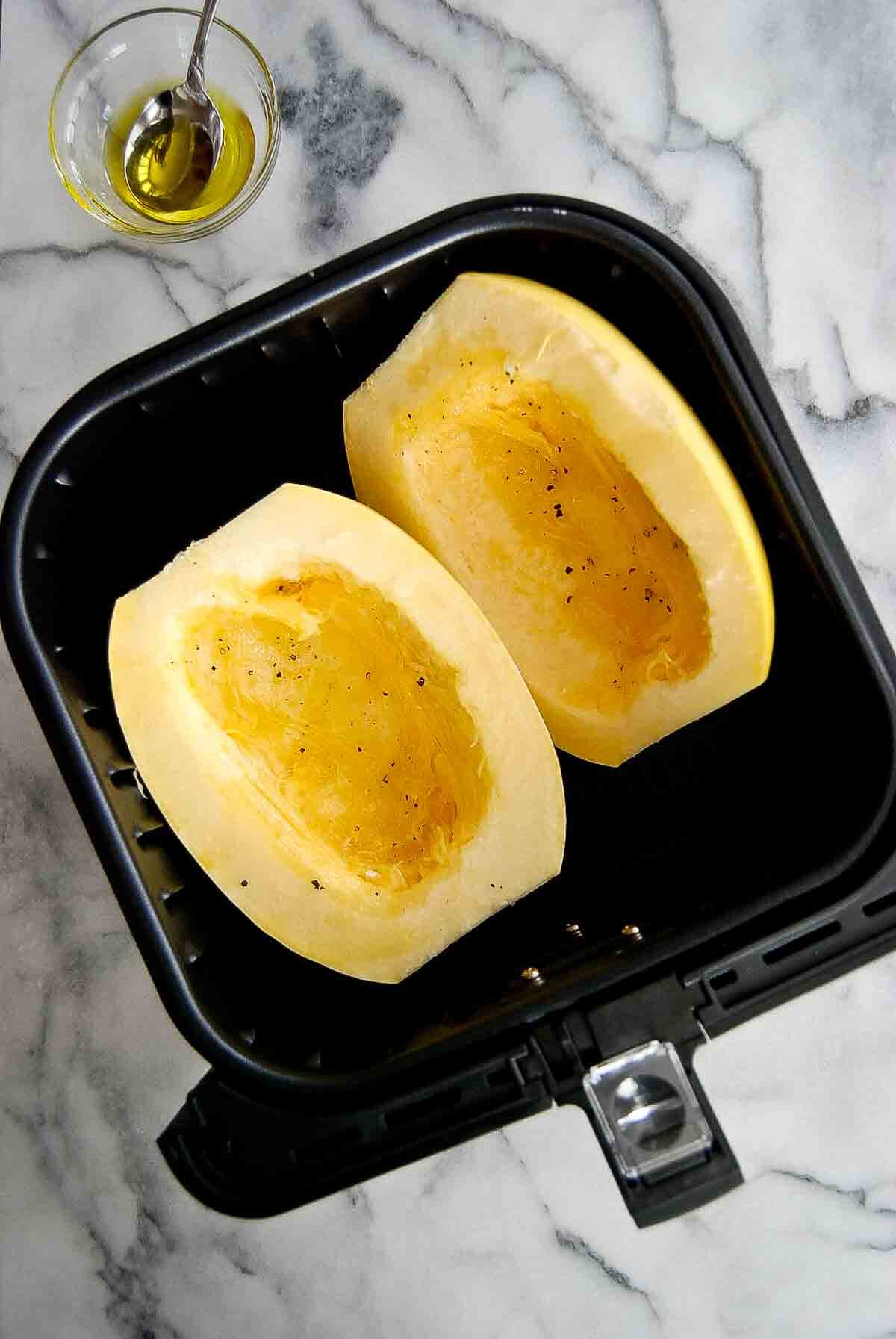 two halves of spaghetti squash placed in air fryer.