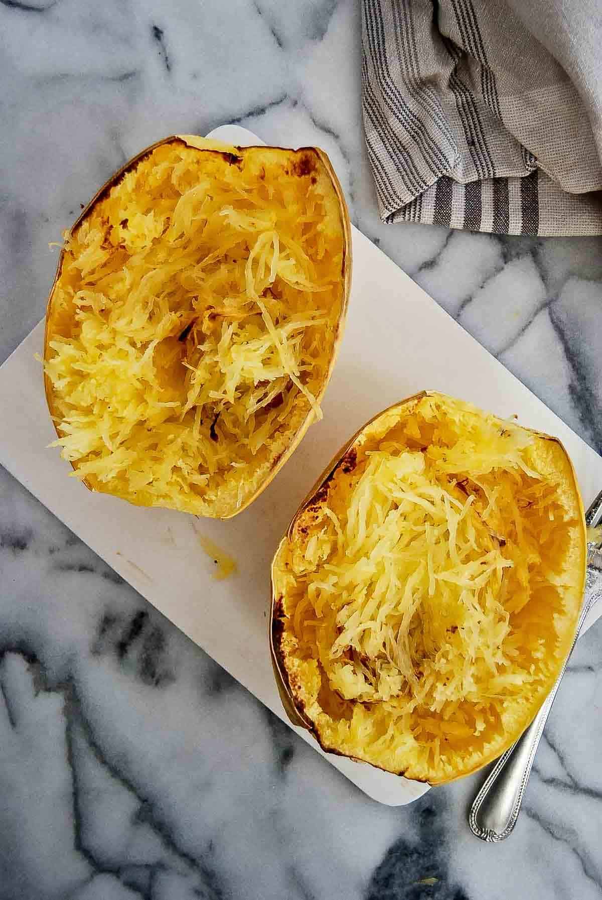 two air fryer spaghetti squash halves, fluffed with a fork.