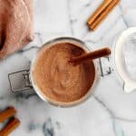 cinnamon sugar mixture in glass container with cinnamon stick sticking out.