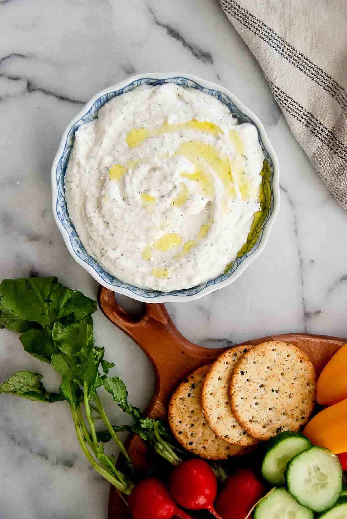 bowl of cottage cheese ranch dip with veggies and crackers on the side.