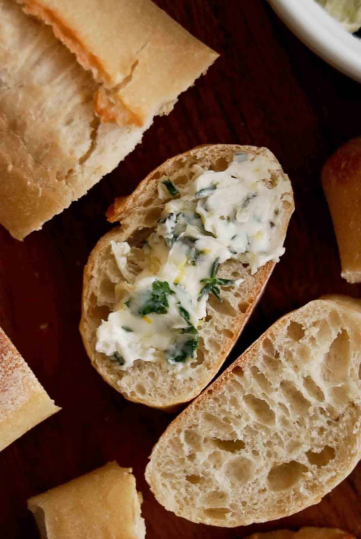 roasted garlic butter with herbs spread onto a baguette.