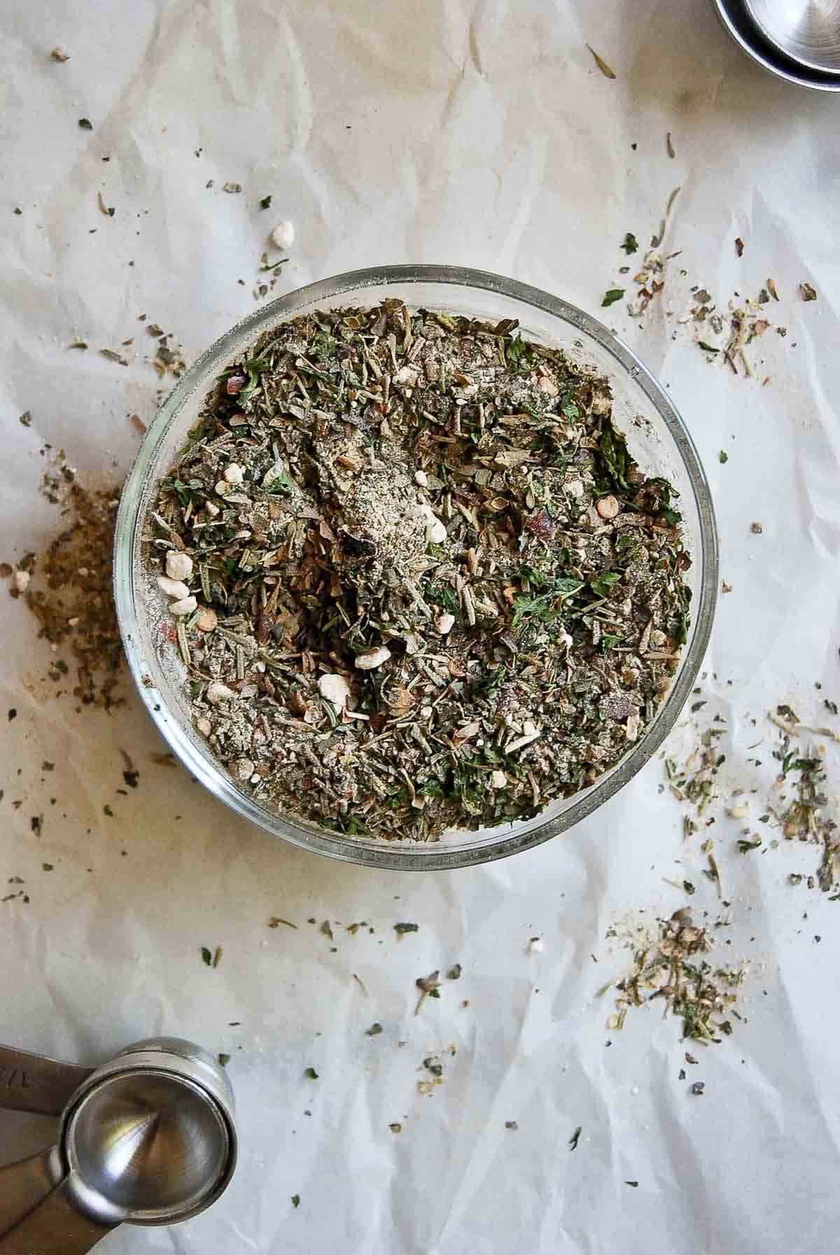 bowl of seasoning for spaghetti sauce with measuring spoons on the side.