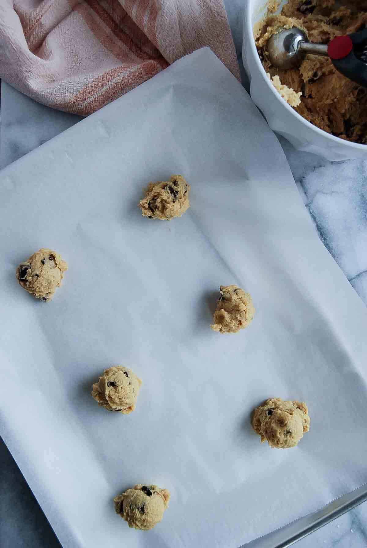 balls of chocolate chip cookie dough on baking sheet.