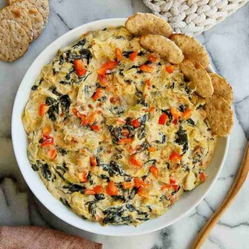 spinach artichoke dip without mayo in bowl with crackers on the side.