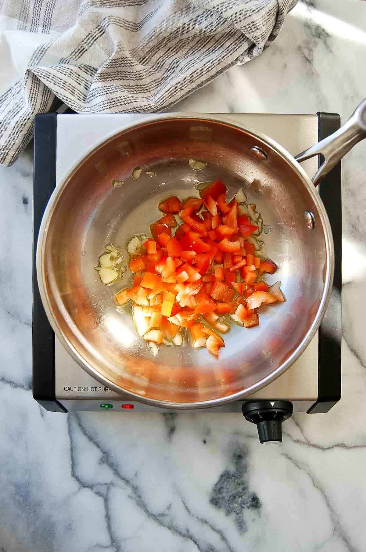 garlic and red pepper sautéing in pan.