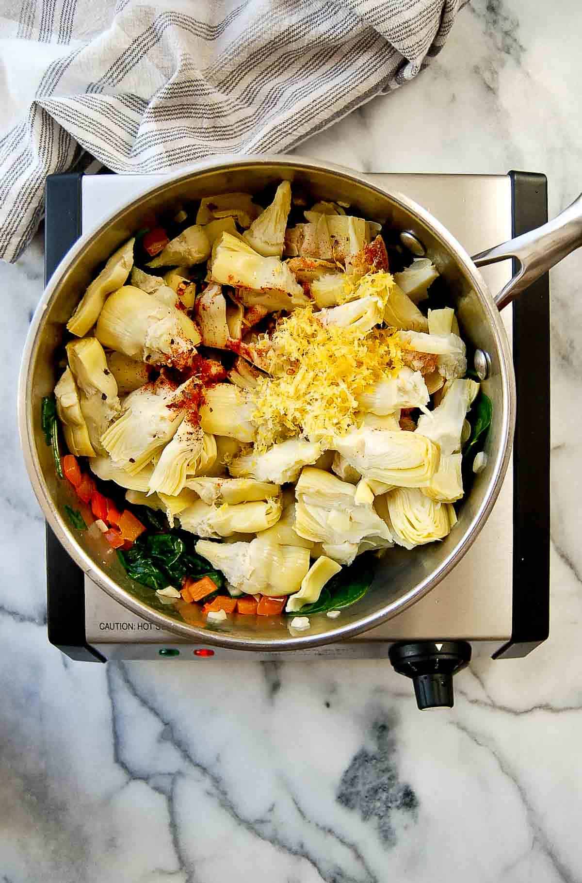 lemon zest in spinach and artichoke dip, cooking in pan.