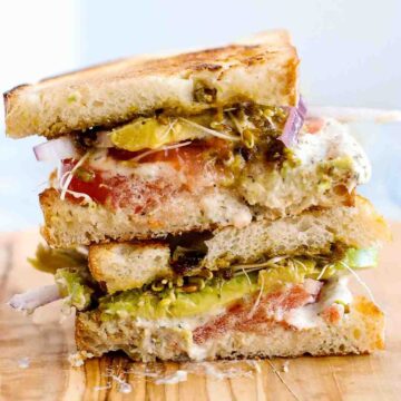 stacked tunacado sandwich on cutting board.