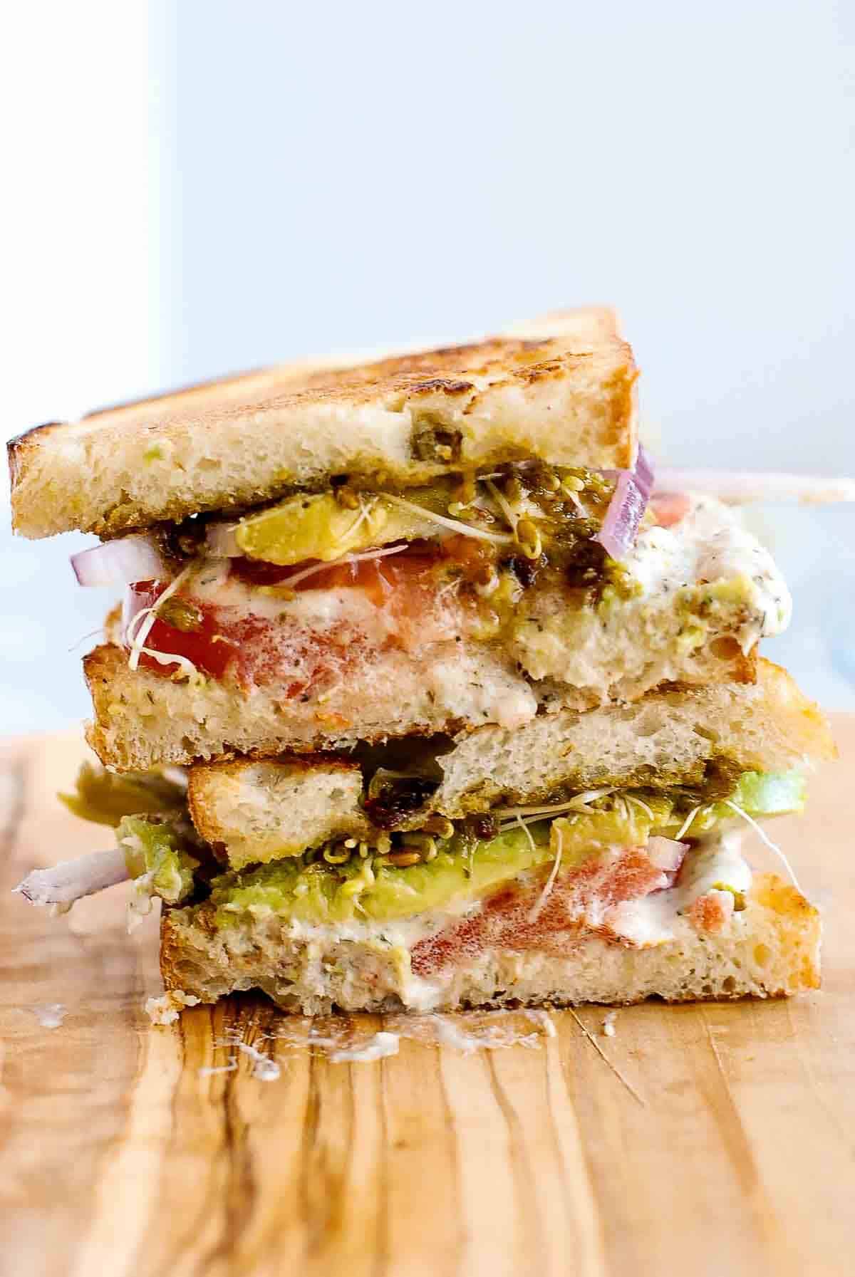 stacked tunacado sandwich on cutting board.