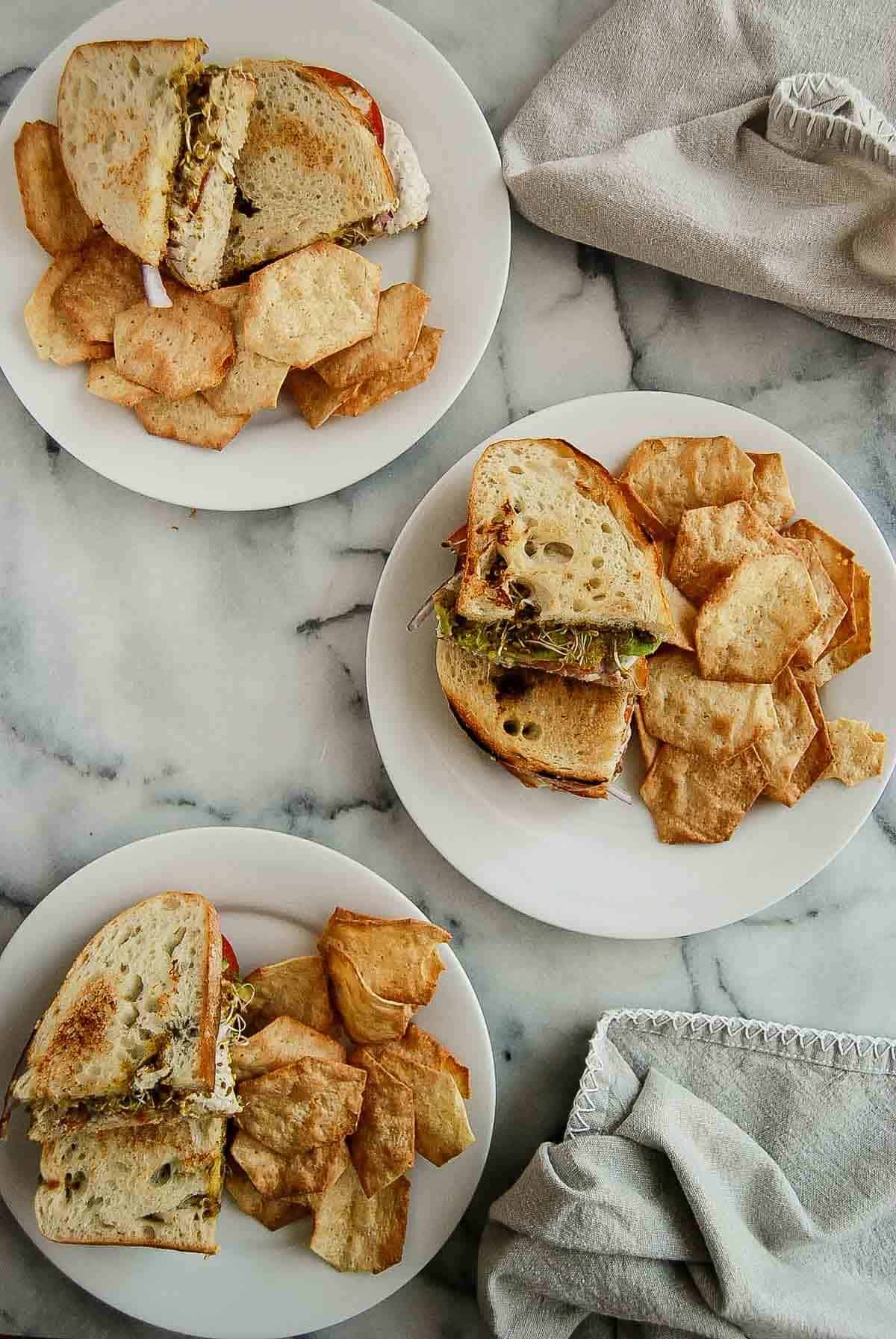 tunacado sandwiches on plates with chips on the side.