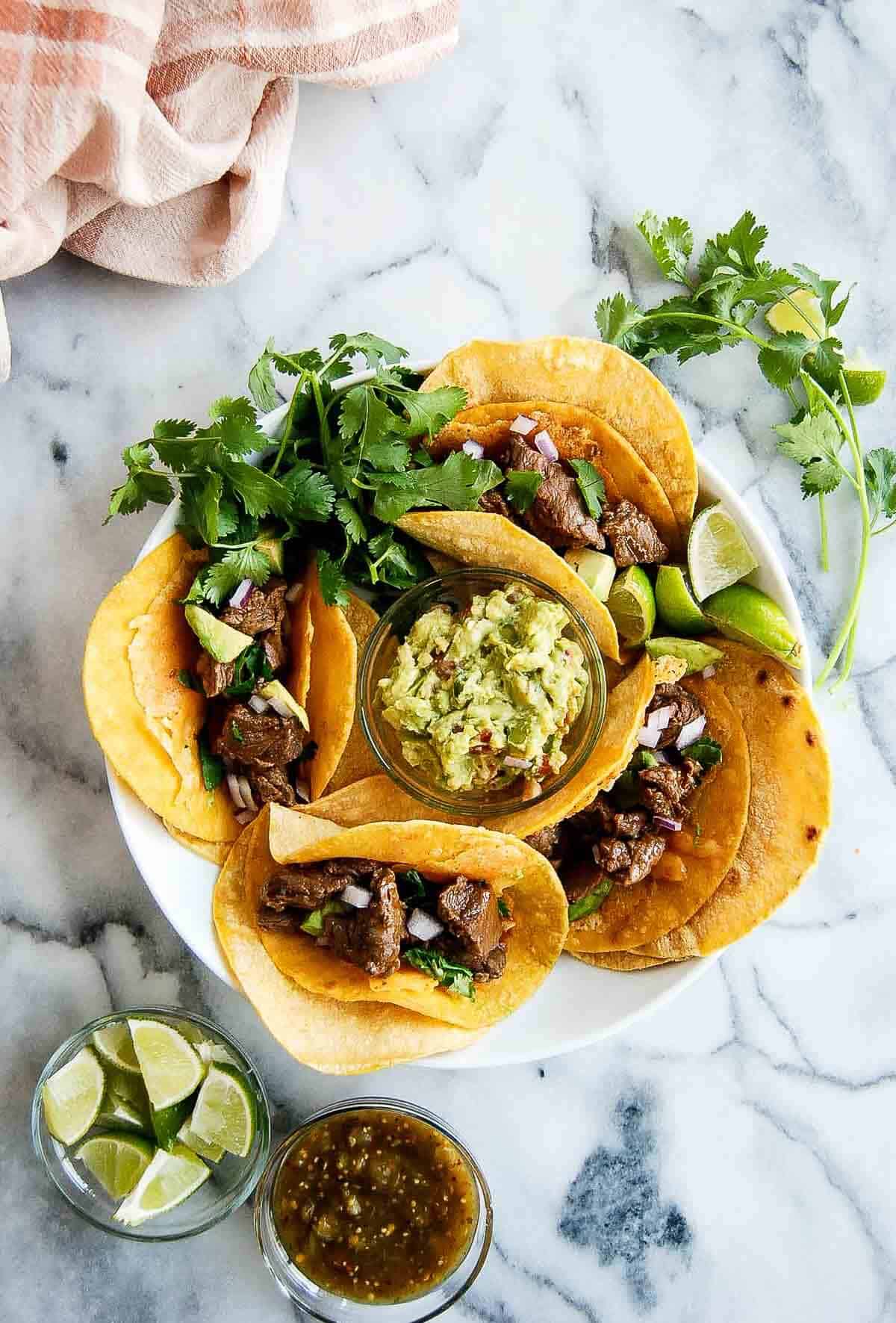 plate with carne asada vampire tacos with toppings on the side.