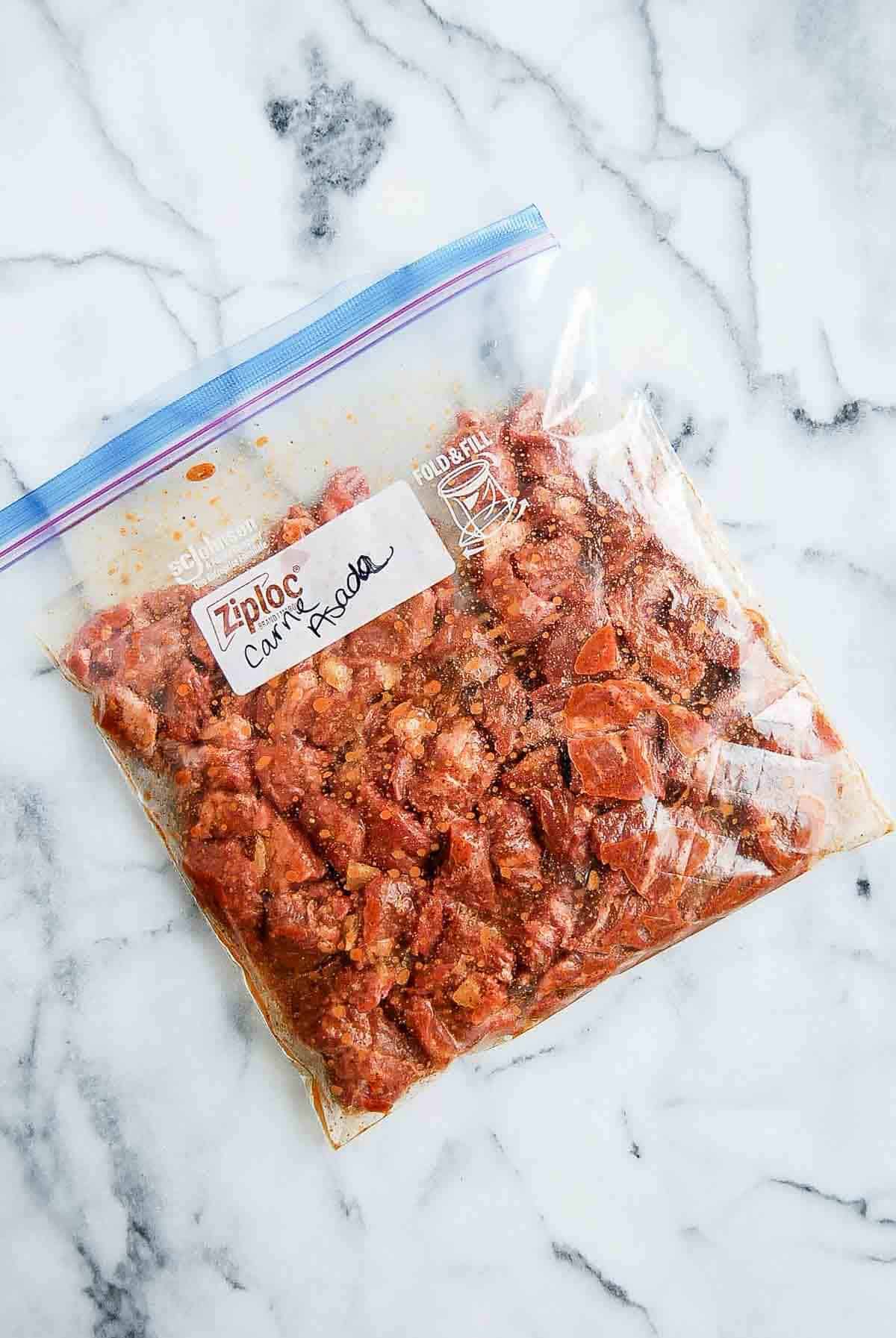 skirt steak marinating in carne asada sauce in a large ziplock bag.