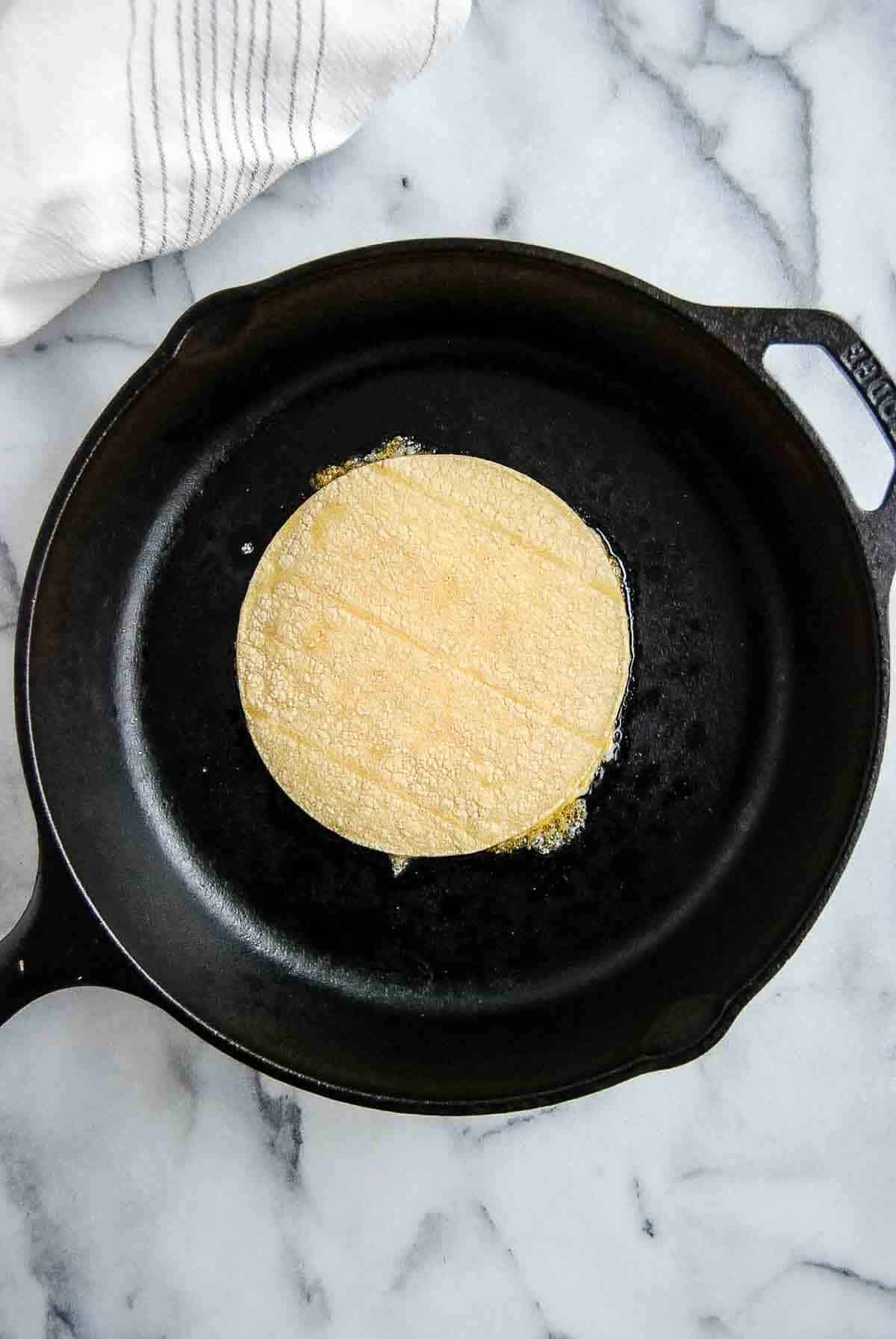 melted cheese on skillet topped with corn tortilla for vampiro tacos.